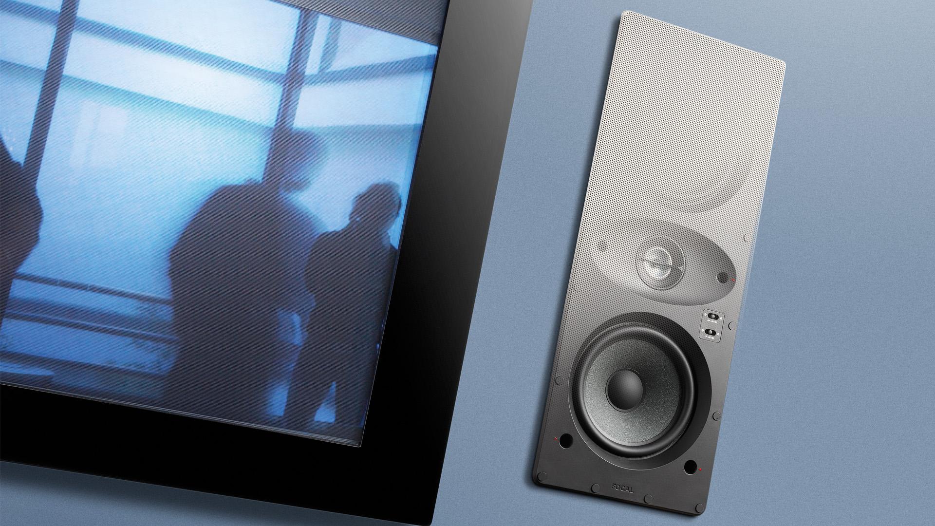 Focal 100 IWLCR5 in-wall speaker beside a screen, shown with a partially revealed grille